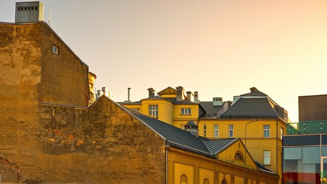 Architectural contrast in Liepaja, Latvia. Old historic brick walls and classic facades meet modern glass building at sunset. Beautiful European city landscape in golden hour light.