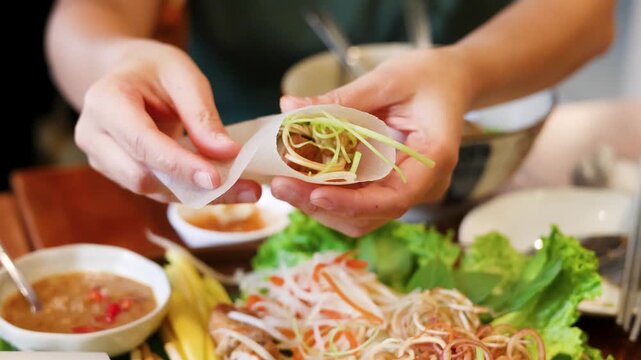 Hands Wrapping Vietnamese Spring Roll with Rice Paper and Fresh Vegetables