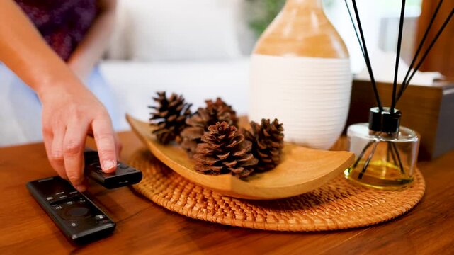Hand Placing Television Remote Control on Wooden Coffee Table Surface
