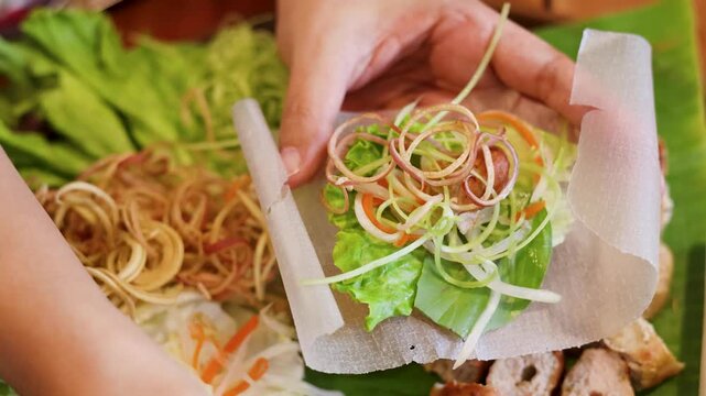 Hands Preparing Vietnamese Nem Nuong Spring Roll with Fresh Vegetables