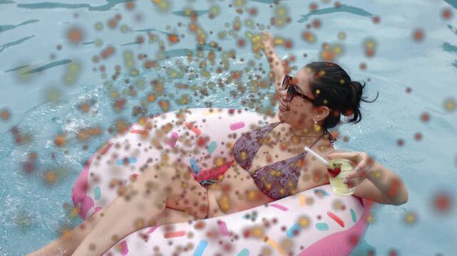 Woman relaxing on pink donut float swinging arm making splash holding drink leisure specks overlay