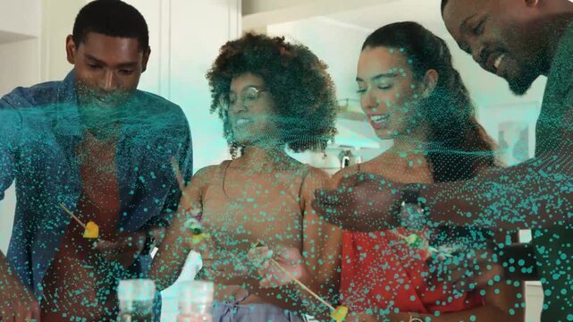 Friends prepping food and threading skewers at counter teal particles marking tasting and sharing