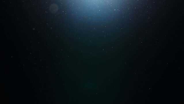 dust particles floating mid air over dark background with some lens flare