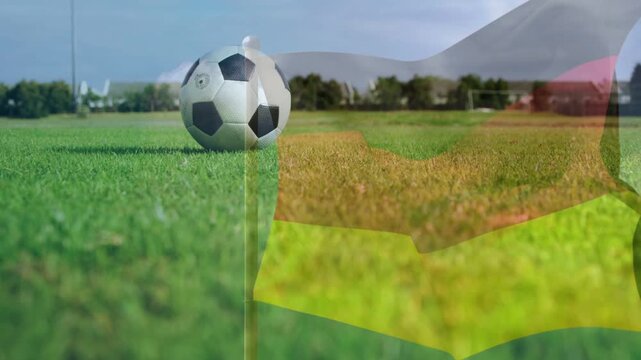 Soccer ball resting on grass while striped flag overlay appearing rippling revealing goal from wind