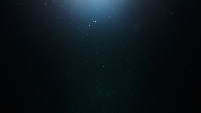 dust particles floating mid air over dark background with some lens flare