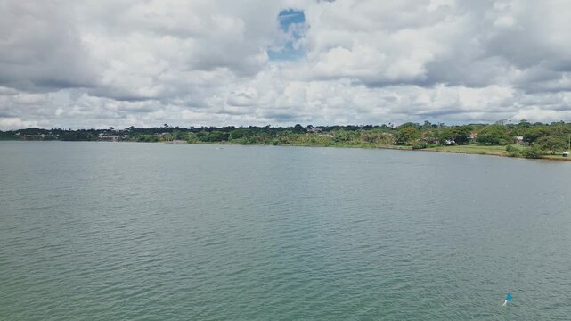 Lago Paranoa in Brasilia Brazil, outrigger canoeing and rowing practices across the expansive lake under a cloudy sky with green shorelines aligning the horizon