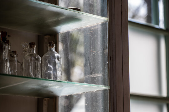 昭和レトロな医院の窓辺に置かれたアンティークな薬品棚と並べられた古いガラス瓶