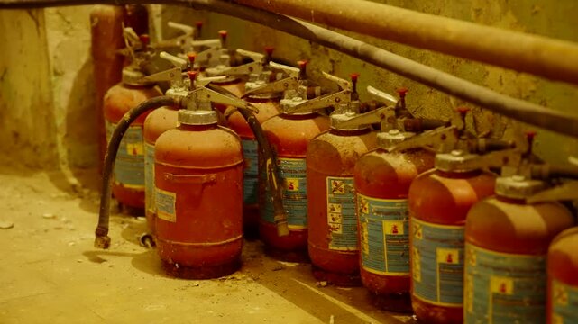 Row Of Old Fire Extinguishers In Abandoned Industrial Building. Expired Extinguishers In Desolate Warehouse