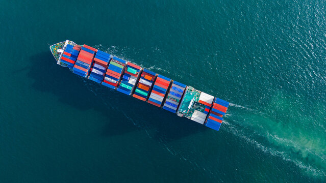 large cargo container ship fully loaded with colorful containers sailing through the deep blue ocean. Global maritime trade, freight transport and logistics business.