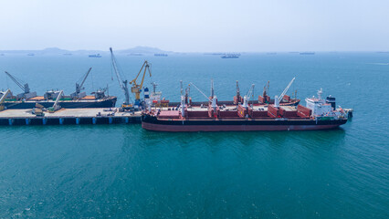 Obraz premium bulk carrier ship loading cargo at a port terminal. Concept of maritime logistics, global trade, industrial export, and international shipping industry infrastructure.