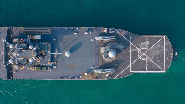 large naval amphibious assault ship being assisted by tugboats in the strategic Strait of Hormuz. Concept of maritime security, naval power projection, and protection of international shipping lanes.