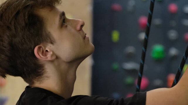 Trainer makes sure rope pulled at same time as client rises up. Young athlete carefully insures beginner in sports center slow motion