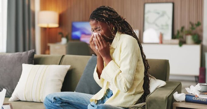 Sick, sneeze or black woman with tissue in lounge, flu season or chronic sinusitis for health crisis. Blowing nose, allergies or person with illness in home for recovery, hay fever or viral infection