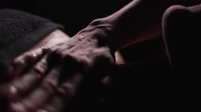 Close-up of woman's chest massage. The masseuse works in dark room.