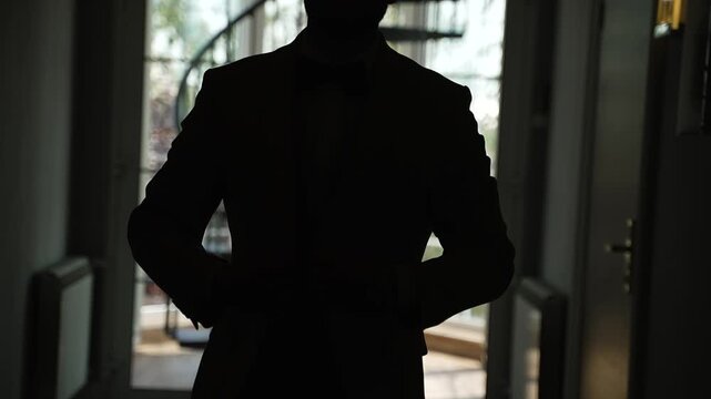 Man in jacket and trousers walks down dark corridor. Groom walking