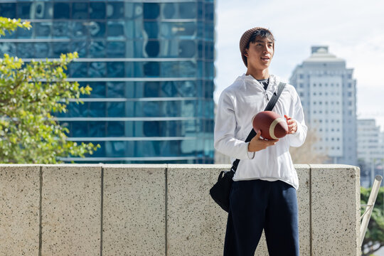 Man on parapet holding football, hearing voice offscreen, with animated sports stats circling ball