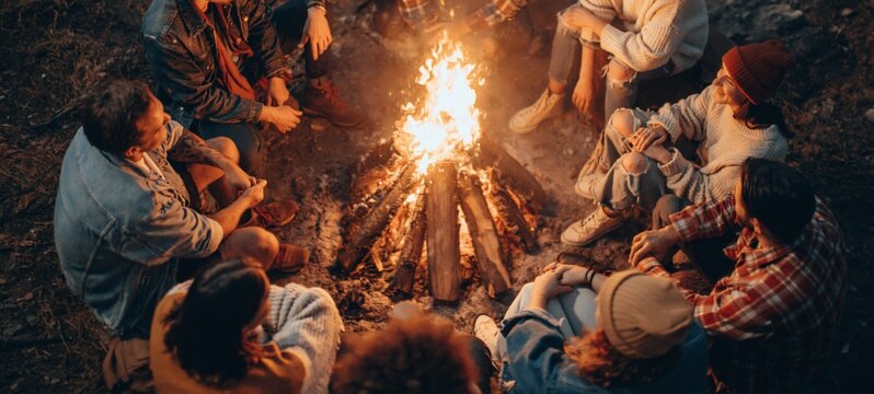 Gathering of friends around a campfire outdoors at night.