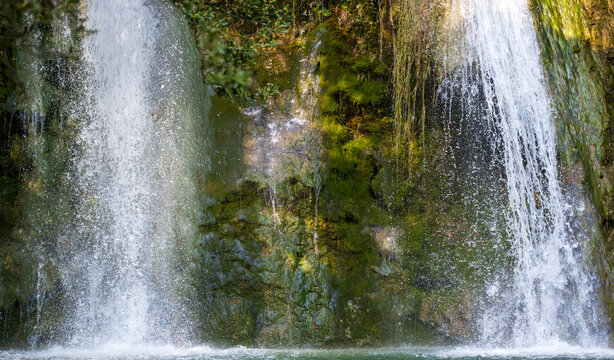 Gouffre waterfall in Cotignac, Provence, France. Twin cascades flowing over mossy limestone cliffs into clear water in Vallon Gai