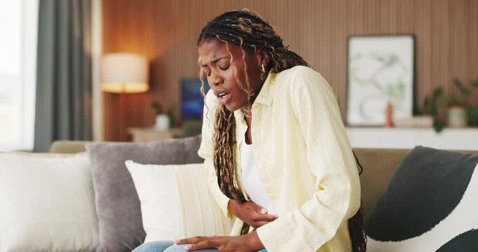 Stomach pain, sofa and black woman in home with menstruation, constipation or food poisoning. Endometriosis, belly ache and African female person in living room with ibs, indigestion or cramps.