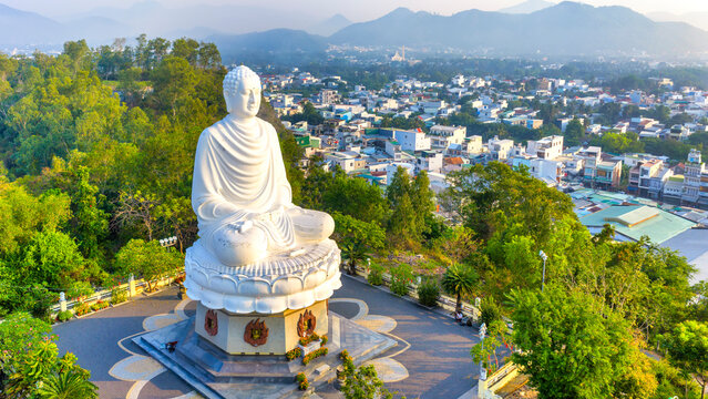 A majestic view of the giant white Buddha statue at Long Son Pagoda, Nha Trang, Vietnam peacefully seated atop a hill overlooking the city.