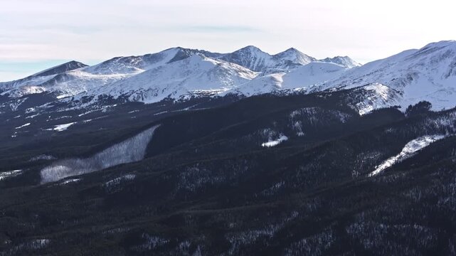 A wide-angle, zoom-in aerial drone shot of snowy peaks surrounding Dillon and Frisco near Breckenridge in Colorado's Rocky Mountains.