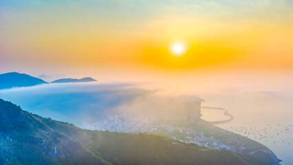 Naklejka premium A breathtaking sunrise view over the mountains surrounding Nha Trang city, Vietnam. Where golden sunlight spreads across a sea of clouds.