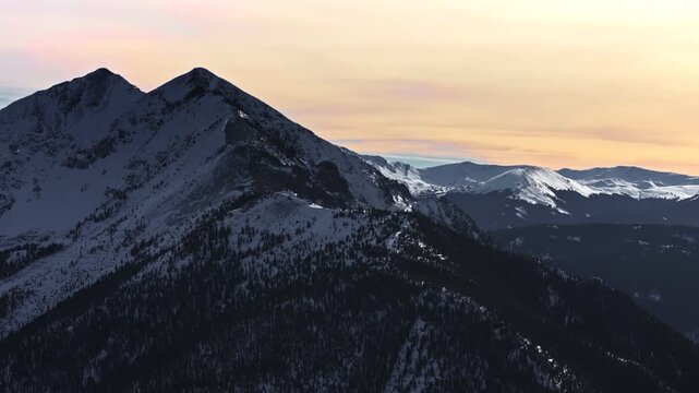 A cinematic, high-flying 70mm-style aerial drone shot of snowy peaks surrounding Dillon and Frisco near Breckenridge in Colorado's Rocky Mountains.