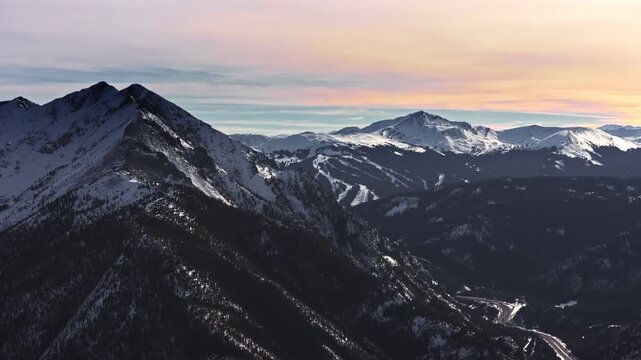 A cinematic, high-flying wide-angle aerial drone shot of snowy peaks surrounding Dillon and Frisco, slowly revealing the ski slopes of Breckenridge Ski Resort in Colorado's Rocky Mountains.