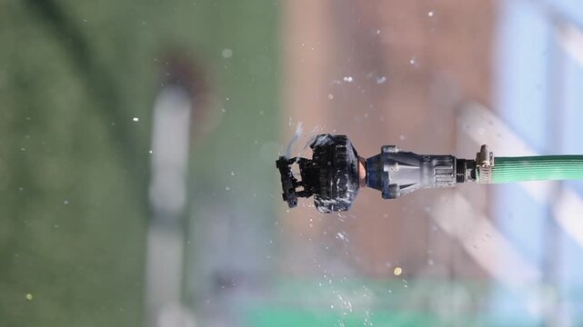 Vertical format bubbler sprinkler dribbles water from hanging hose