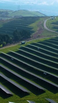 Vertical Video of Hill Landscape Aerial with Solar Panel Array. Technology and nature, sustainable energy production. Climate change solutions, and future infrastructure. 9:16 reels format.
