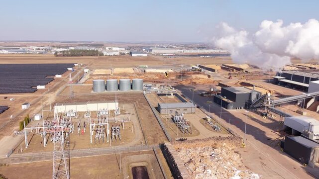 Factory Skyline With Smoke Clouds. Paper Manufacturing Site With Steam Emissions Visible. Aerial Perspective Of Polish Paper Mill With Steam Plumes Rising Above Storage Areas