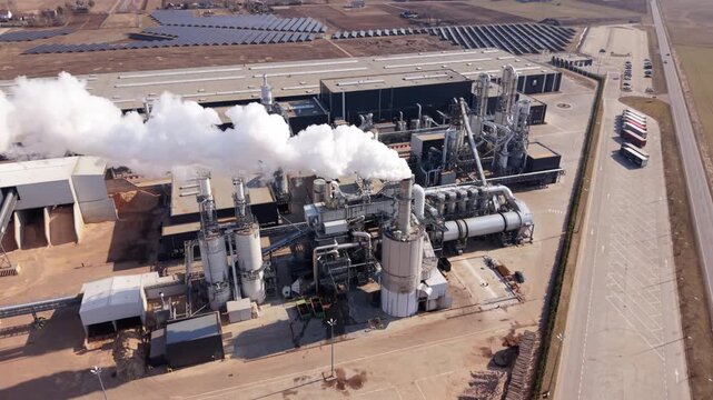 Aerial View Of Polish Industrial Complex With Solar And Steam Emissions. Overhead Perspective Of Polish Industrial Facility Featuring Extensive Solar Arrays And Conveyor Systems