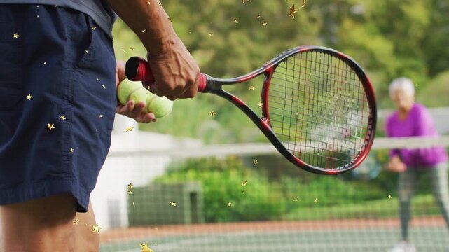 Senior man adjusting racket grip and tossing ball toward woman, sports practice with gold stars