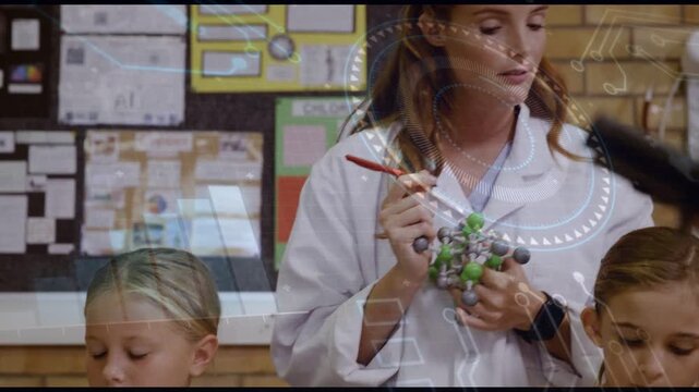 Teacher coming in holding model teaching science while class writing under faint circuit overlay