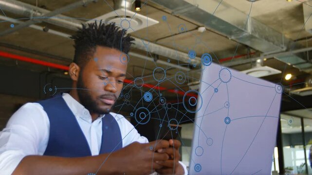 Man scrolling phone in office, blue net expanding as camera widens revealing laptop showing tech