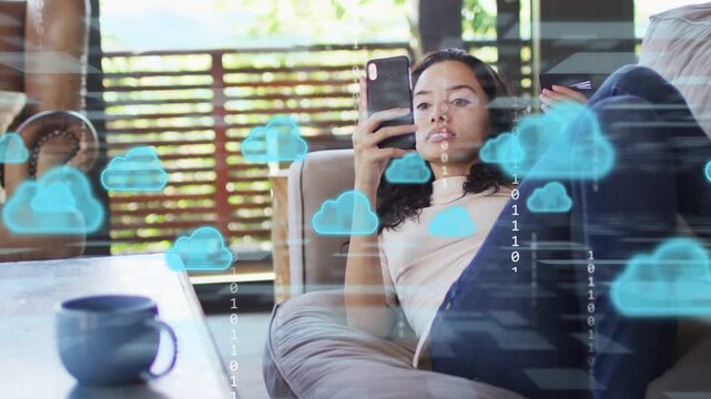 Woman on sofa tapping phone making cloud tech overlay showing binary, growing then fading, smiling