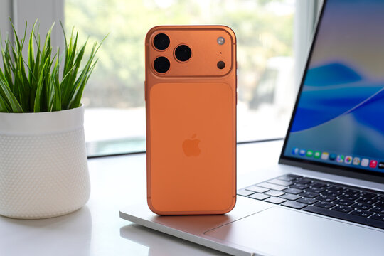 Mobile phone Apple iPhone 17 Pro Max Cosmic Orange unpacked  on the table on the MacBook