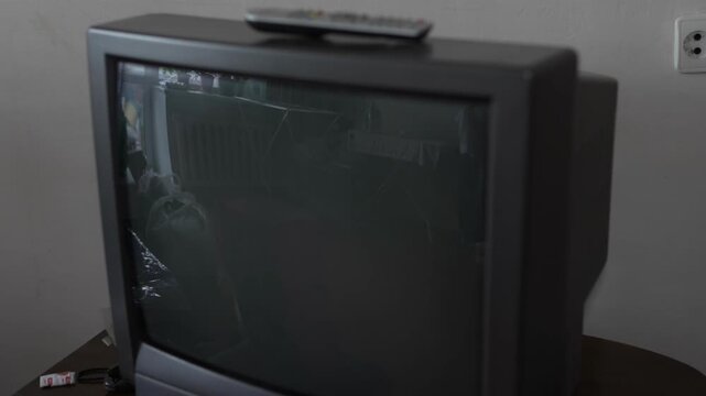 Old black CRT television with remote control on top surface.