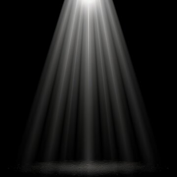 A bright spotlight shines down on a dark background with beams of light