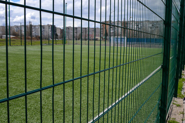 empty football field behind metal fence in park, outdoor sports and recreation concept for training, urban environment, fitness, community space and active lifestyle © Виталина Митрофанова