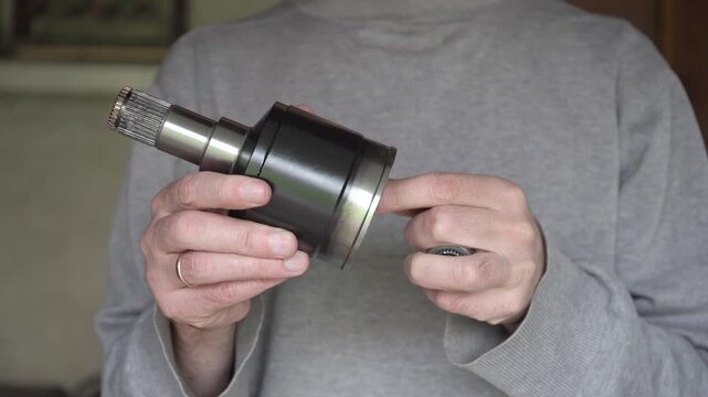 Close-up of a mechanic inspecting a brand new automotive transmission part,  Man holding a new car tripod bearing and CV joint housing