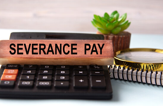 SEVERANCE PAY - words on a wooden block with a calculator in the background