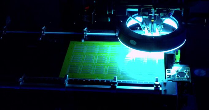 Modern high-tech production. An automated high-precision machine assembles an electronic printed circuit board. A close-up shot of the process.