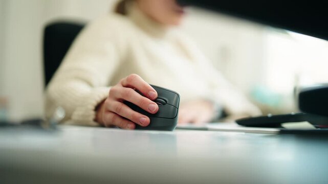 Close-up of an office worker using an ergonomic computer mouse at a clean and modern workspace.