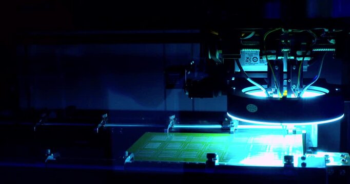 Close-up video of a modern high-tech automated machine precisely assembling an electronic printed circuit board.