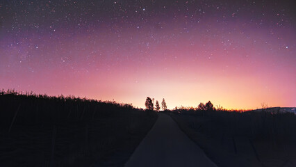 Starry night sky over rural road with colorful twilight horizon   Rozgwieżdżone niebo nad wiejską drogą z kolorowym horyzontem o zmierzchu © Adrian White