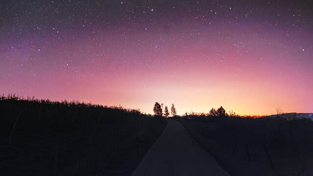 Starry night sky over rural road with colorful twilight horizon | Rozgwieżdżone niebo nad wiejską drogą z kolorowym horyzontem o zmierzchu