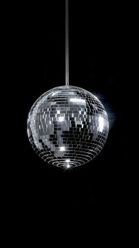 Shiny disco ball hanging against a black background.