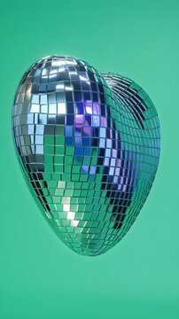 Shiny disco ball shaped like a heart against green background.