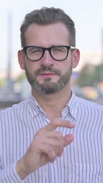 Outdoor Young Adult Man with Finger on Lips, Please be Quiet, Vertical Video
